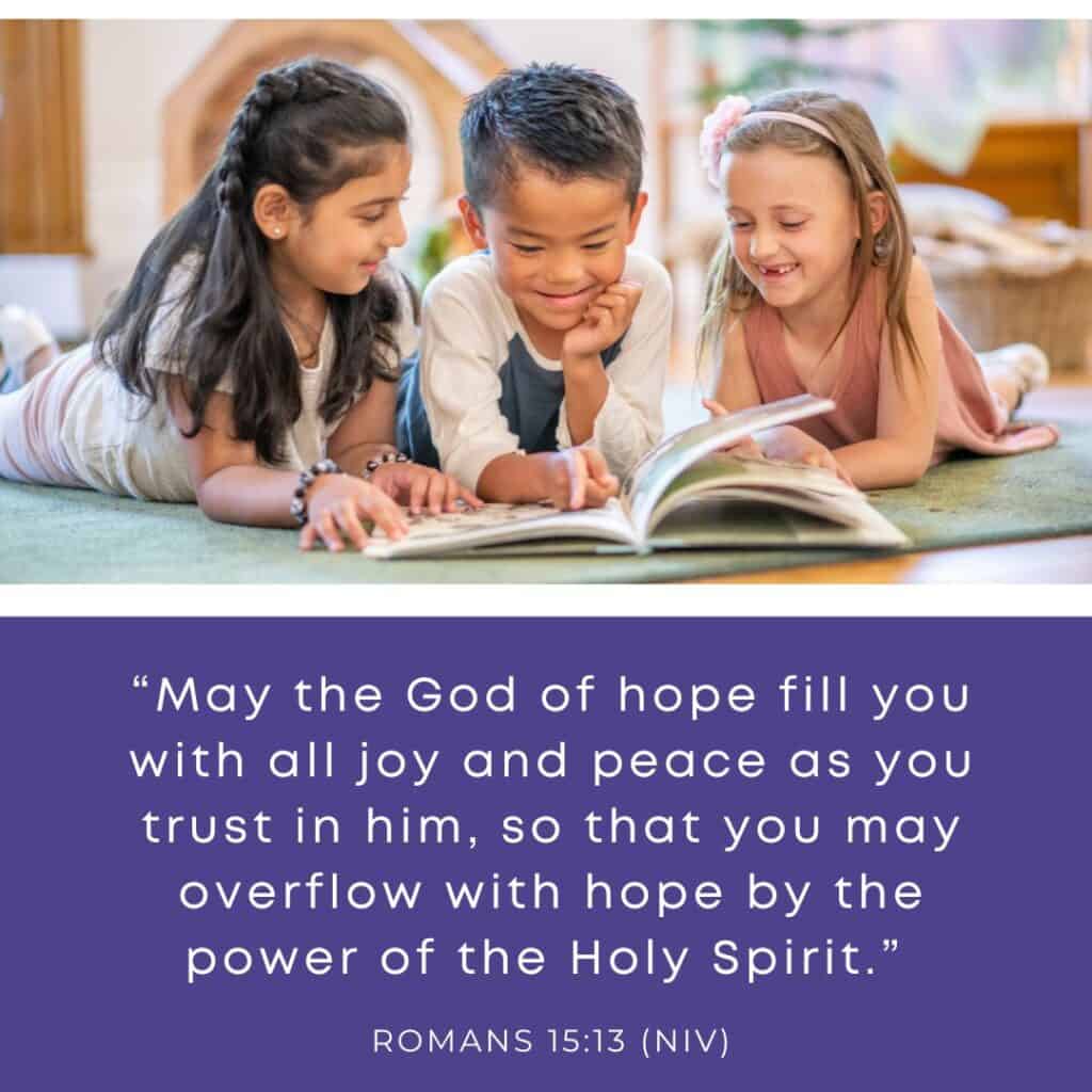 Three children smiling as they read the Bible together, reading Romans 15:13: "May the God of hope fill you with all joy and peace as you trust in him, so that you may overflow with hope by the power of the Holy Spirit."